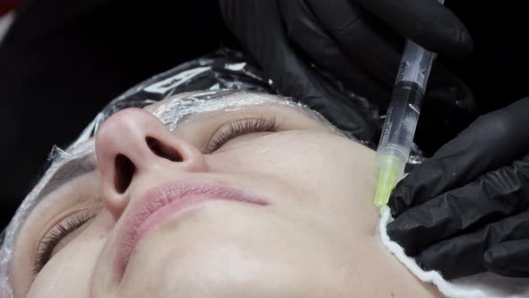 Cosmetologist is making multiple injections biorevitalization with hyaluronic acid in woman face alt