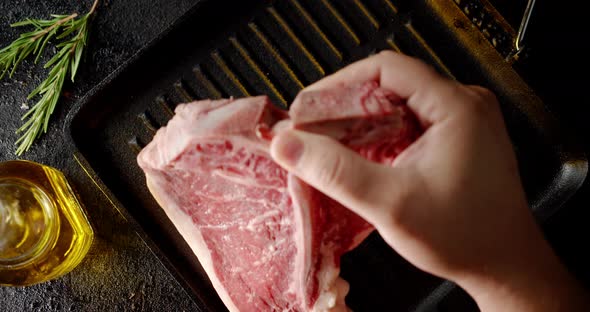 The Men's Hand Puts the Steak T-bone Raw Beef in the Pan.  alt