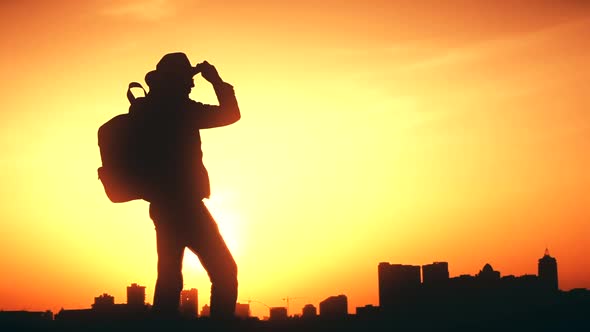 Silhouette of a Man with a Backpack Against Bright Sky Sunset