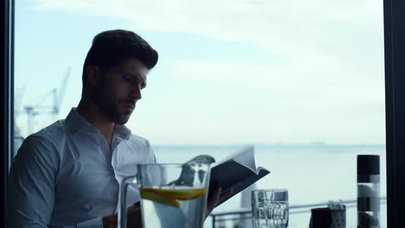 Relaxed Man Customer Reading Wine List in Panoramic Luxury Lounge Bar Portrait alt