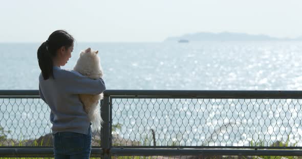Woman hug with her dog and look at the sea alt