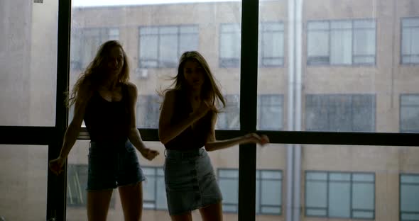 Women Silhouettes Dance Against Large Window and Building alt