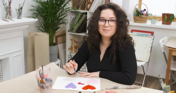 Girl is Painting Hearts on Paper for Saint Valentine's Day Homemade Gift