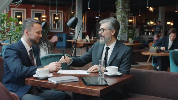 Businessmen in Formalwear Using Smartphones Touching Screen at Table in Cafe alt