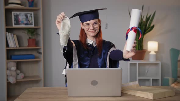 Young Female Student Happily Takes Off Mask From Face Rejoices at End of School Year Online Sitting alt