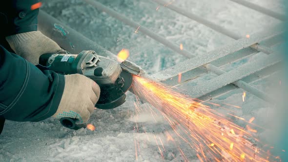 Worker on Winter Day Treats Metal Gates with Angle Grinder and Sparks Fly