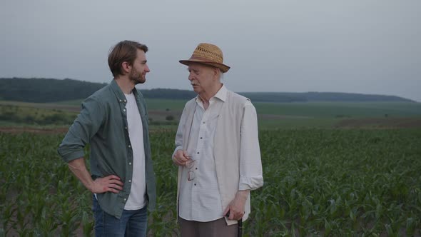 Smiled Man Talk and Hug Each Other on the Green Field alt