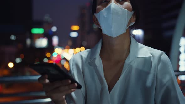 Young Asia businesswoman in fashion clothes wearing face mask using smart phone typing text message.