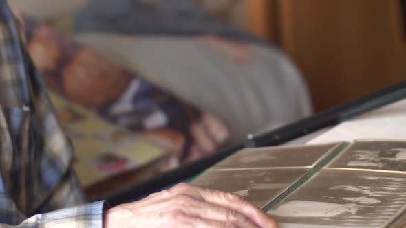 Positive Caucasian pensioner 70 years old with a cane examines black and white old photos flipping t alt