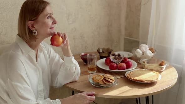 Woman is Sitting at a Table an Apple in Her Hand She Looks at Him at an Apple