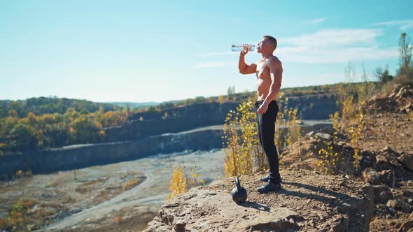 Sportsman is drinking water from a bottle outdoors. alt