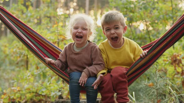 Two Children Screaming Loudly While Sitting in a Hammock alt