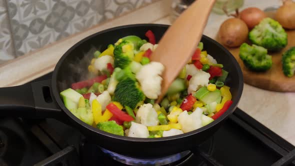 Cooking of frozen vegetables in frying pan. Frozen vegetables frying on hot pan