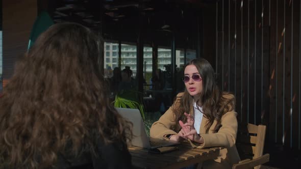 Pair of Brunette Women Are Sitting in Street Restaurant Veranda in Sunny Day
