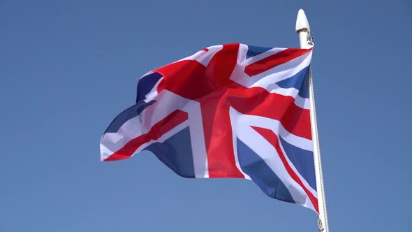 UK Flag Fluttering Against Blue Sky in Slow Motion