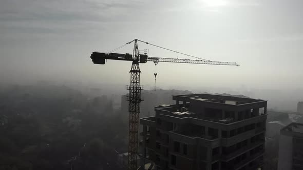 Birds eye view on tower crane in fog standing next to residential building.  alt