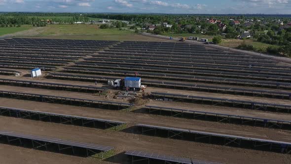 Crane Truck with a Transformer at the Back in Between the Rows of Solar Panels alt