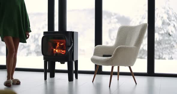 Woman Sits on Chair By the Fireplace at House on Nature alt