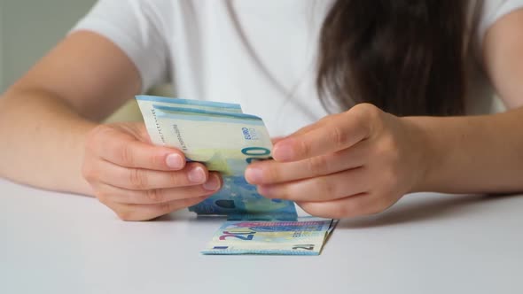 A Woman Counts Bills for 20 Euros and Taps Her Fingers on the Table alt