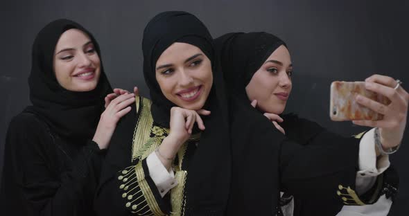 Group of Young Beautiful Muslim Women in Fashionable Dress with Hijab Using Mobile Phone Taking alt