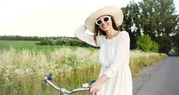 Woman Walking with Bicycle on Country Road