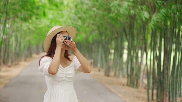 Young happy woman enjoying and taking a photo in the bamboo forest