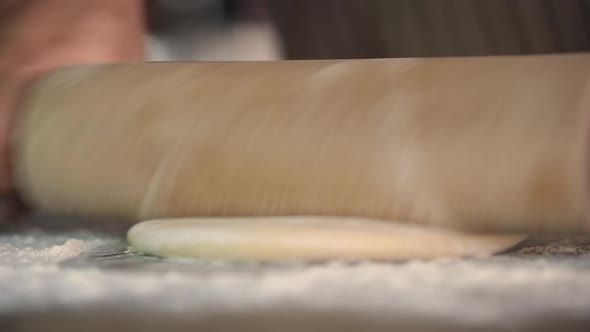 Man rolls out the dough with a rolling pin