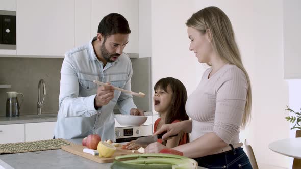 Happy Young Parents Couple and Little Girl Cooking Dinner alt