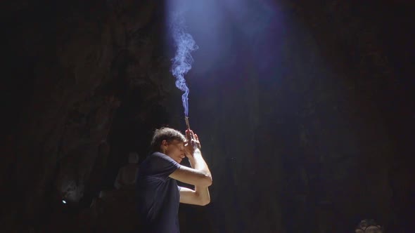 Slowmotion Shot of a Young European Man Which Is Praying Holding Smoking Aroma Sticks in His Hands alt