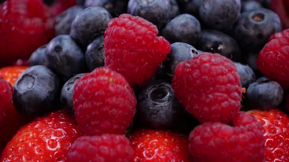 Strawberries, raspberries and blueberries rotating on a black background