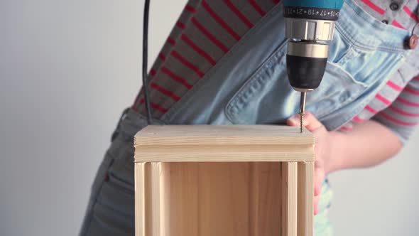 a Woman Does a Non-female Job - Drills a Hole with a Screwdriver in a Wooden Box, Slow Motion