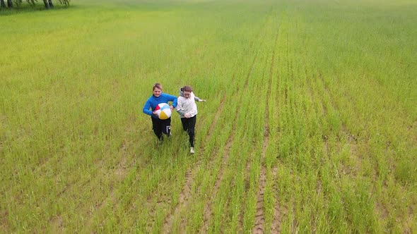 Happy Boy and Girl Running with a Ball in the Field Slow Motion alt
