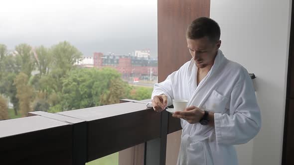 A Young Man, a Man in A White Coat, Drinks Coffee on The Balcony