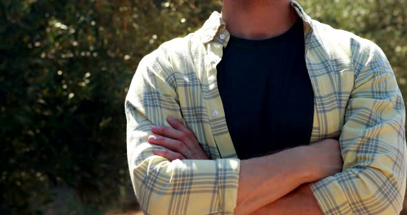 Smiling man standing with arms crossed in olive farm alt