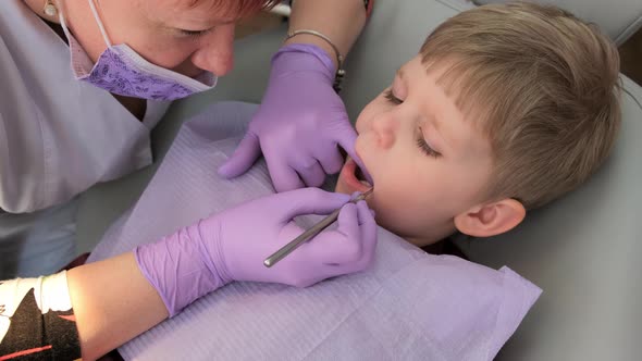 Female Dentist examining boy's teeth in clinic. A small patient in the dental chair .