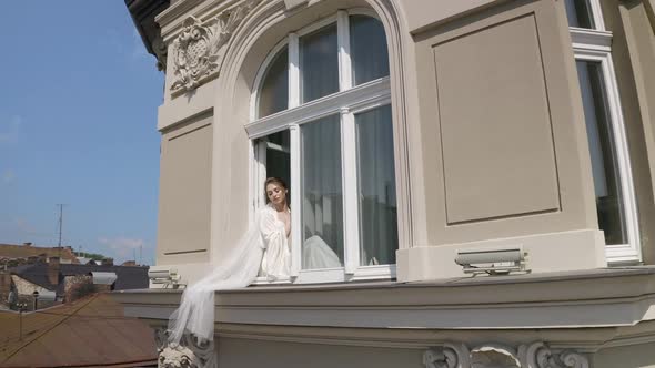 Bride in Boudoir Dress Sitting on Window Sill Wedding Morning Preparations Woman in Night Gown Veil alt