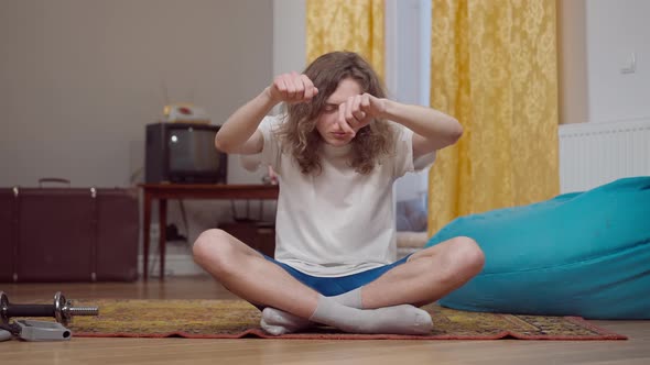 Funny Caucasian Young Man Dancing Sitting in Lotus Pose in Vintage Style Living Room alt