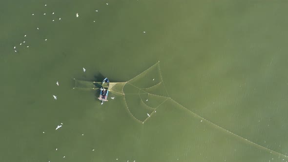 AERIAL: Fishermans Casting Nets in the Green Baltic Sea with Gulls Flying Around Searching for Fish