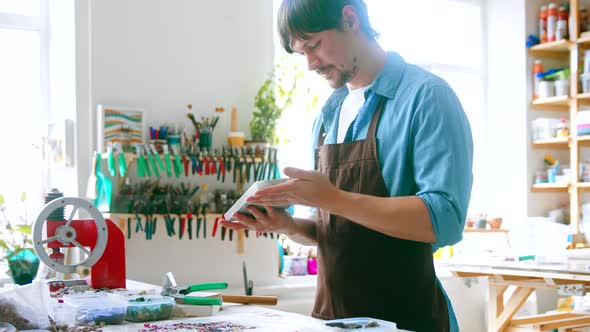 A young master in uniform examining a piece of stone alt
