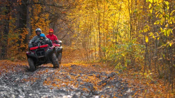 Three People Riding Atv in the Autumn Forest on the Muddy Track alt