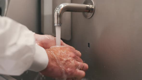 a Man Washes His Hands Under a Touchless Tap Water