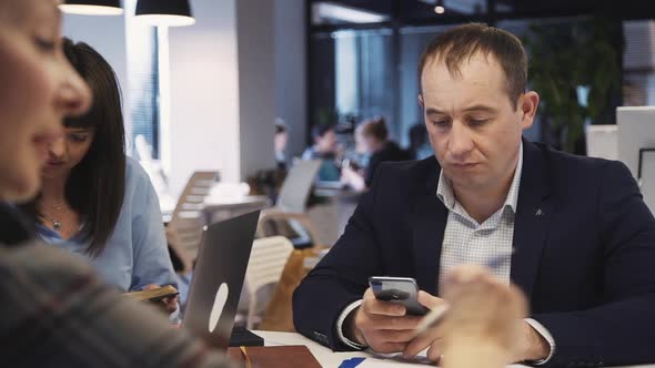 Mature Man Using Smartphone and Working in Office