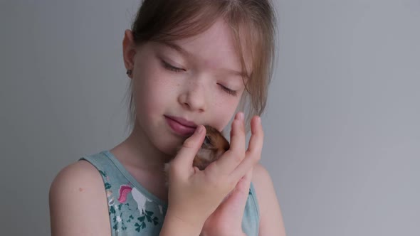 Little Cute Girl Holding a Hamster in Her Arms Playing with Him