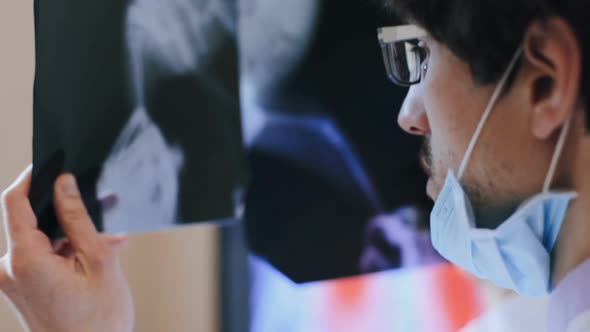 The doctor examines the X-ray for a possible bone fracture. alt