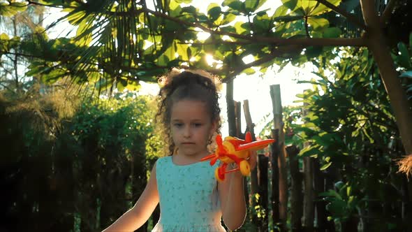 Happy Child Runs With A Toy Airplane On A Sunset Background. alt