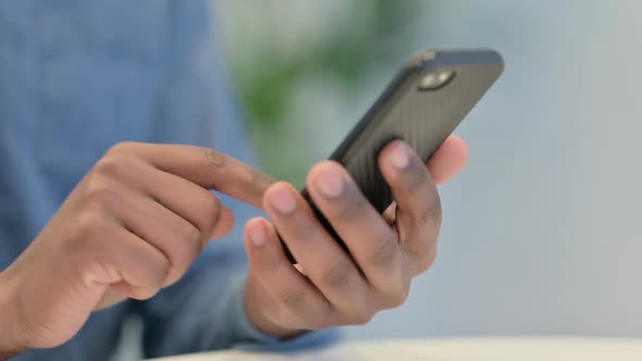Close Up of Hands of African Man Typing on Smartphone alt