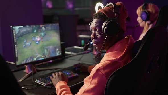 African American Bearded Casually Dressed Man Wearing Headset Playing a Popular Online Team Game alt