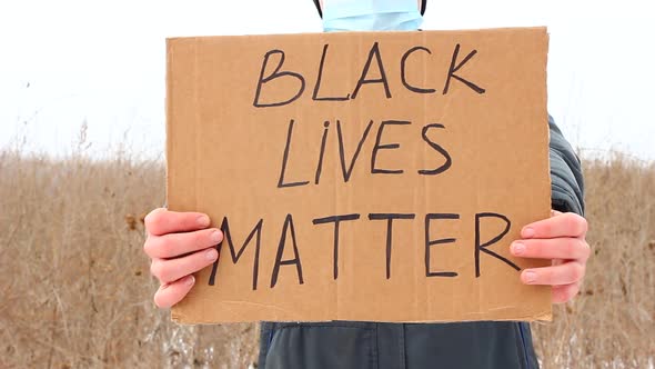 A Caucasian Man Holds a Sign with the Words BLACK LIVES MATTER alt