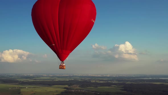 Red Heartshaped Balloon with People Over Green Fields and Forests