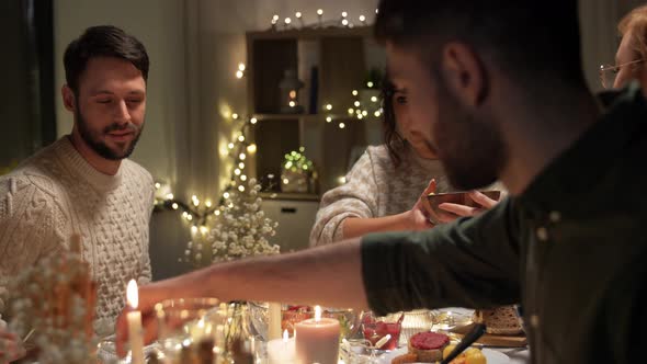 Happy Friends Having Christmas Dinner at Home alt